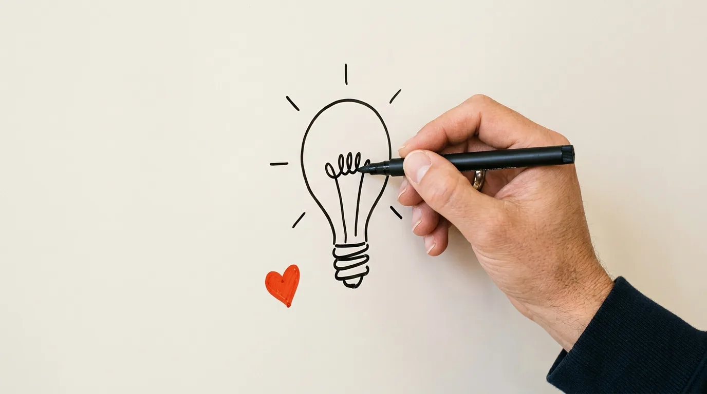 A hand sketching a lightbulb on a whiteboard